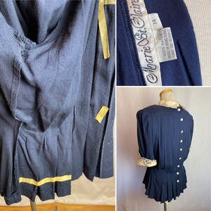 May include: A navy blue rayon dress with a white lace collar and cuffs. The dress has a pleated skirt and a button closure in the back. The dress is labeled "Harriet St. Clair" and "100% Rayon Made in Hong Kong Care See Reverse".