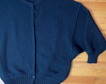 May include: A black knitted cardigan with a button closure. The cardigan has a ribbed hem and cuffs. The label reads "Jean Pierre" and "Made in Italy".