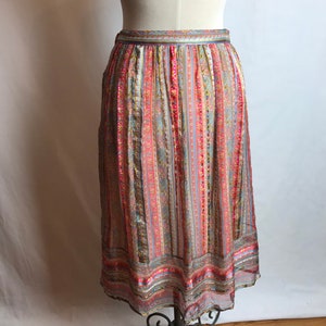 May include: A long, flowing skirt with a colorful striped pattern in shades of pink, blue, and gold. The skirt is made of a sheer fabric and has a gathered waistband.