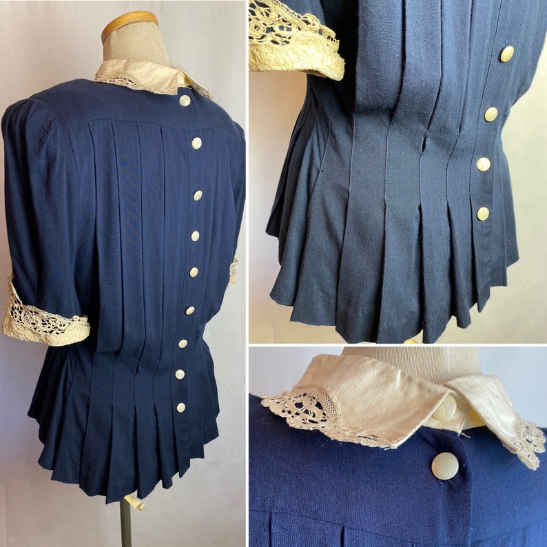 May include: A navy blue blouse with a white lace collar and cuffs. The blouse has a fitted bodice and a pleated skirt. The blouse has a button-up front and a back.
