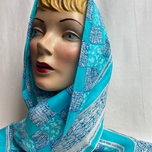 Puede incluir: Una bufanda azul y blanca con un diseño a cuadros. La bufanda está hecha de seda y tiene una textura suave y fluida.
