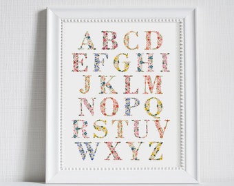May include: A white framed print with a floral alphabet design. The letters are made of colorful floral patterns. The letters are in a white font on a white background.