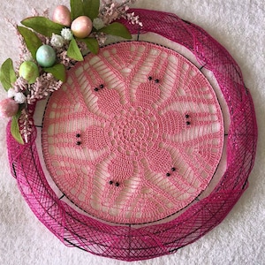 May include: Pink crocheted wreath with pink and green floral accents and pastel colored Easter eggs.
