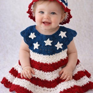 May include: A crochet dress and matching bucket hat featuring a patriotic design. The dress has a dark blue yoke with white star appliqués, followed by horizontal red and white scalloped stripes. The hat mirrors this red, white, and blue pattern.