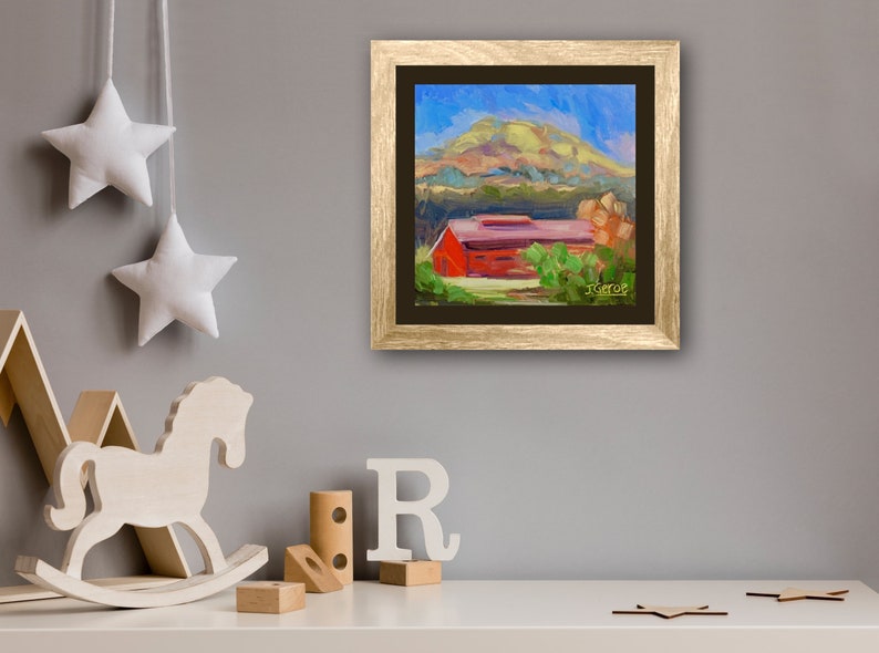 May include: A framed painting of a red barn with a green roof, surrounded by trees and a hill in the background. The sky is blue with white clouds. The painting is in a gold frame.