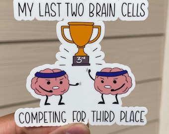 May include: A white sticker with a humorous illustration of two brain cells competing for third place in a race. The sticker features a gold trophy with a "3rd" place ribbon and the text "My last two brain cells competing for third place."