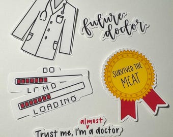 May include: Five stickers with a medical theme. One sticker is a white doctor's coat. Another sticker says "future doctor" in black cursive writing. A third sticker is a yellow circle with a red ribbon and the text "Survived the MCAT". A fourth sticker is a progress bar with the text "Loading" and a fifth sticker says "Trust me, I'm a doctor" with the word "almost" written above the text.