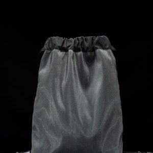 May include: A gray drawstring bag with black drawstrings and black straps. The bag has a white logo that says "YMWW".