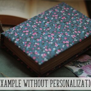 May include: A hardcover book with a floral fabric cover in teal, adorned with pink and white flowers. The book's pages are aged, and the text "EXAMPLE WITHOUT PERSONALIZATION" is displayed at the bottom.