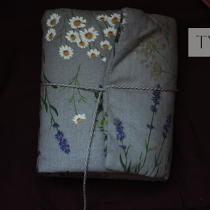 May include: A wrapped package featuring a gray fabric with floral patterns of white daisies and purple lavender. The package is tied with twine and has the text "TYPE 2" in a white rectangle.