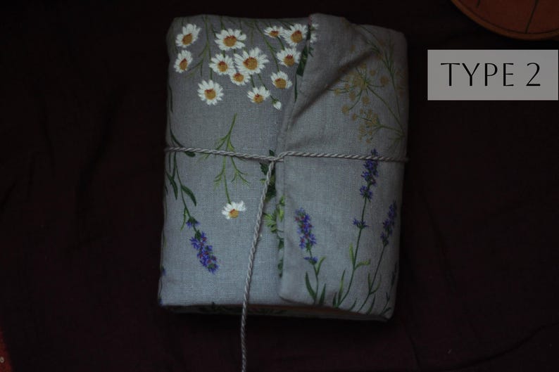 May include: A wrapped package featuring a gray fabric with floral patterns of white daisies and purple lavender. The package is tied with twine and has the text "TYPE 2" in a white rectangle.