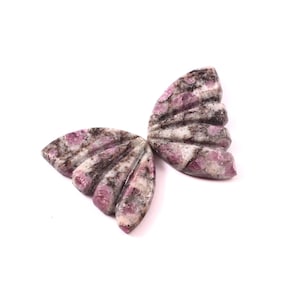 Op de afbeelding: Twee gegraveerde stenen vlindervleugels met een wit en roze gevlekt patroon. De vleugels zijn gegraveerd met een waaiervormig ontwerp.
