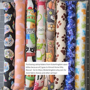 Puede incluir: Ocho juguetes largos y cilíndricos de tela para gatos, dispuestos verticalmente. Los patrones incluyen gatos coloridos estilo calavera, siluetas de gatos naranjas, gatos con ropa de invierno, gatos rosas, caras de gatos, huellas de patas marrones, gatos sobre fondo galáctico y pequeños gatos naranjas y verdes.