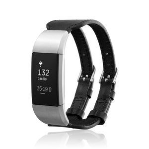 Op de afbeelding: Een zwart leren bandje met zilveren hardware voor een fitness tracker. Het bandje heeft een gespsluiting en wordt getoond op een witte achtergrond. Het scherm van de tracker toont "132 cardio" en "35:19.0".