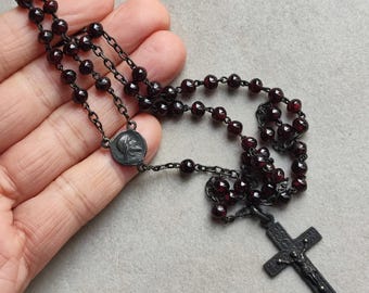 Terço antigo, com peça central e cruz em prata, feito de contas cor de granada.