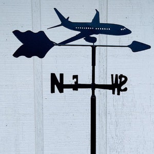 May include: Black metal airplane weather vane with a directional arrow and compass points labeled N, W, S, and E.