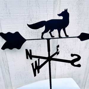 May include: Black metal fox weather vane with a compass rose and arrow. The arrow points north, east, south, and west.