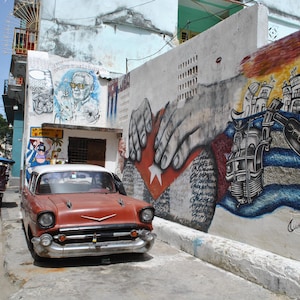 Arte callejero cubano, La Habana, autos antiguos, escenas callejeras, cultura cubana, fotografía urbana, murales coloridos, arte de viaje, bandera cubana.