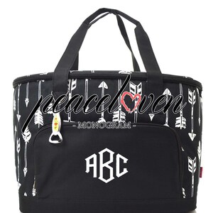 Może przedstawiać: Czarno-biała torba termiczna z zamkiem błyskawicznym i g&oacute;rnym uchwytem. Torba ma wz&oacute;r białych strzałek i tekst "MONOGAM" i "ABC" w kolorze białym.