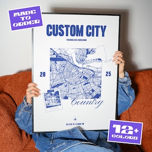 May include: A framed poster with the text "CUSTOM CITY" and a blue map of a city. The poster is on a couch and has the text "MADE TO ORDER" and "12+ COLORS" on the side.