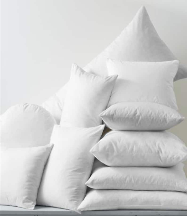 May include: A stack of white pillows of various sizes and shapes. The pillows are arranged in a pyramid shape, with the largest pillow at the top and the smallest pillows at the bottom.