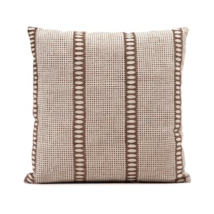 Puede incluir: Una almohada de color marr&oacute;n y blanco con un dise&ntilde;o geom&eacute;trico. La almohada tiene forma cuadrada y est&aacute; hecha de un tejido suave y texturizado.