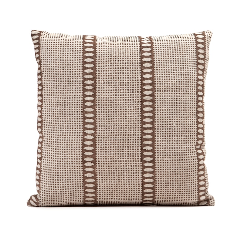 Puede incluir: Una almohada de color marr&oacute;n y blanco con un dise&ntilde;o geom&eacute;trico. La almohada tiene forma cuadrada y est&aacute; hecha de un tejido suave y texturizado.