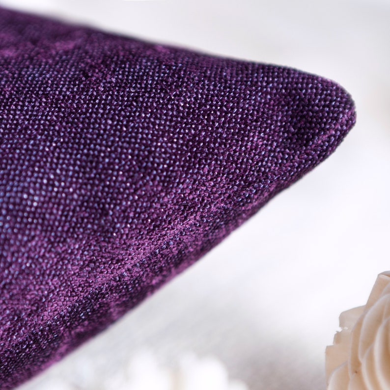 May include: Close-up of a deep purple velvet pillow with a textured surface.