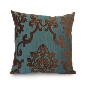 May include: A teal blue throw pillow with a brown damask pattern. The pillow is soft and plush, and would add a touch of elegance to any room.