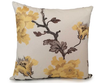 Puede incluir: Una almohada de color crema con un patrón floral. Las flores son amarillas y marrones y tienen un aspecto texturizado.
