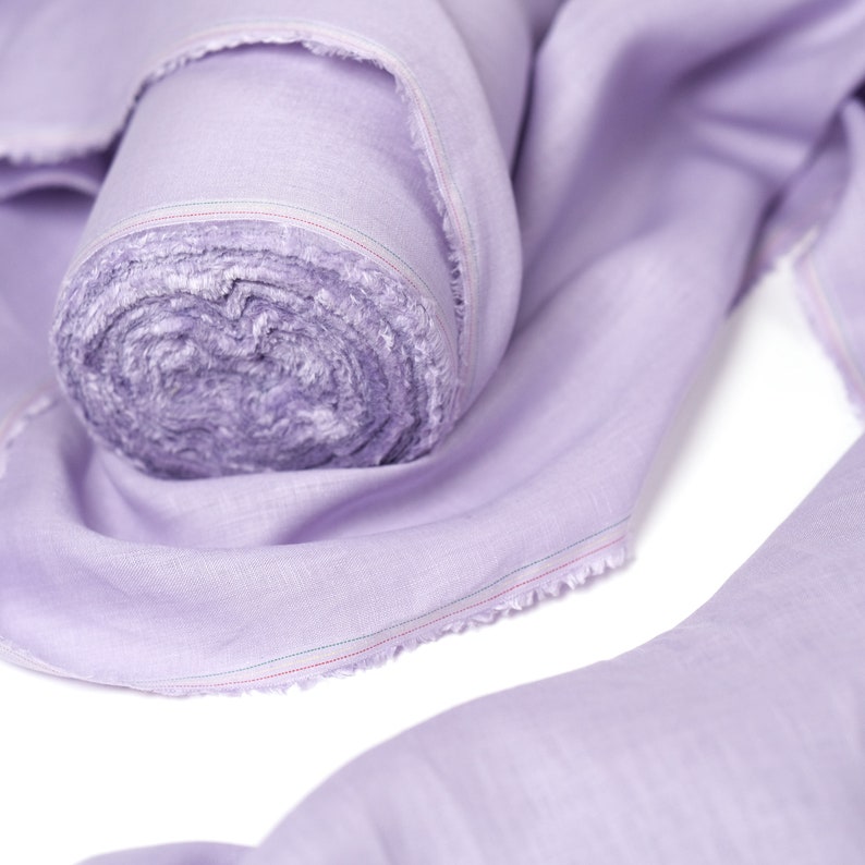 May include: A roll of lavender-colored fabric with a slightly frayed edge. The fabric is rolled up and the end is folded over.