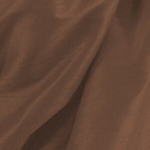 May include: A close-up of a brown fabric with a smooth, silky texture. The fabric is draped and folded, creating soft, flowing lines.
