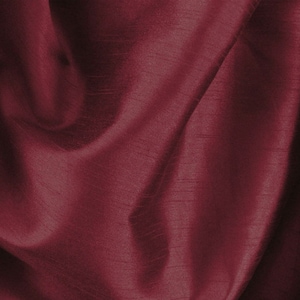 May include: A close-up of a deep burgundy fabric with a smooth, silky texture. The fabric is draped and folded, creating soft, flowing lines.