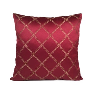 May include: Red pillow with a gold geometric pattern. The pattern features a repeating design of diamonds and fleur-de-lis.
