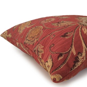 May include: Red and gold floral patterned throw pillow with a textured fabric.