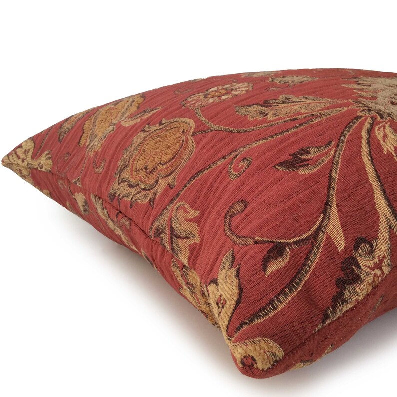 May include: Red and gold floral patterned throw pillow with a textured fabric.