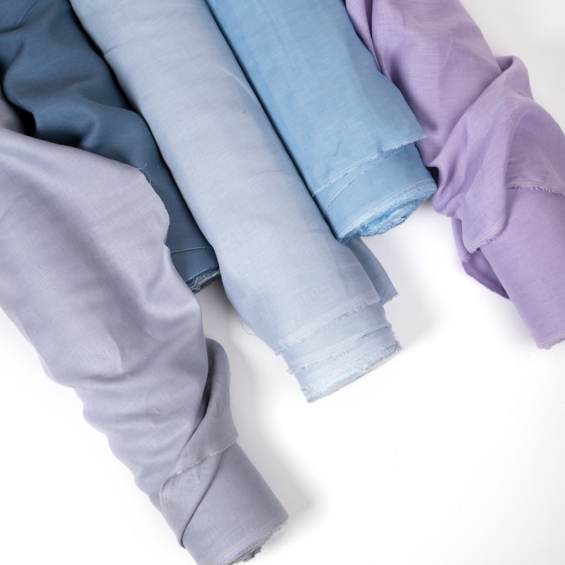 May include: Four rolls of fabric in shades of blue and purple. The fabric is soft and has a subtle sheen.