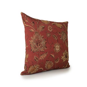 May include: A red throw pillow with a floral pattern in shades of brown and gold. The pillow is made of a textured fabric and has a square shape.