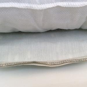 Puede incluir: Primer plano de una almohada blanca con cremallera. La almohada est&aacute; rellena de un material blanco y esponjoso.