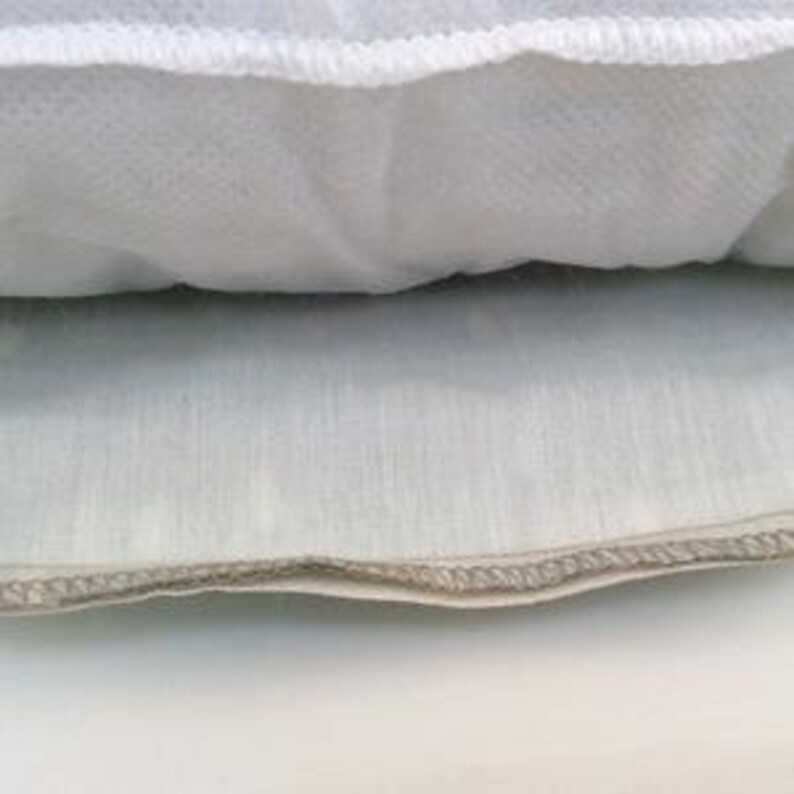 Puede incluir: Primer plano de una almohada blanca con cremallera. La almohada est&aacute; rellena de un material blanco y esponjoso.