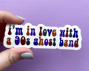 Puede incluir: Una pegatina blanca con el texto "I'm in love with a 90s ghost band" en letras coloridas de estilo retro.