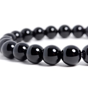 Könnte beinhalten: Ein schwarzes Armband mit runden, glänzenden Perlen.