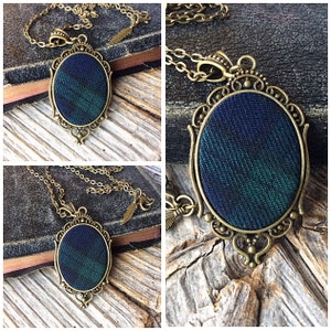 May include: A gold chain necklace with a pendant featuring a green and blue plaid fabric design in an oval frame.