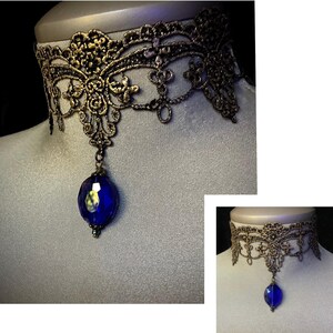 Pode incluir: Um colar de renda dourado com um pingente de cristal azul.