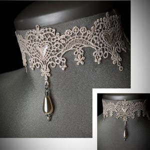May include: A delicate ivory lace choker necklace with a dangling pearl pendant.