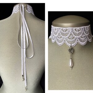 May include: White lace choker necklace with a pearl and flower pendant. The choker is on a white mannequin bust.