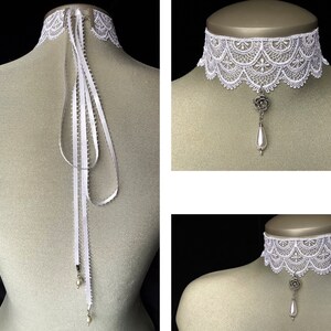 May include: White lace choker necklace with a pearl and flower pendant. The choker has a delicate, scalloped edge and is tied with a white satin ribbon.