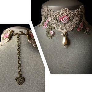 Puede incluir: Un delicado collar gargantilla de encaje blanco con bordados florales rosas y un colgante de perla. El collar tiene una cadena de bronce con un dije en forma de coraz&oacute;n.