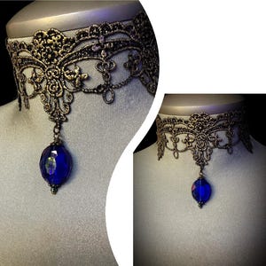 Pode incluir: Um colar de choker de renda dourada com um pingente de cristal azul.