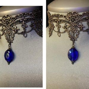 Pode incluir: Um colar de choker de renda dourada com um pingente de pedra preciosa azul.